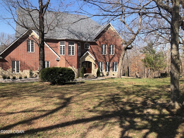 view of front facade with a front yard, brick siding, and stone siding