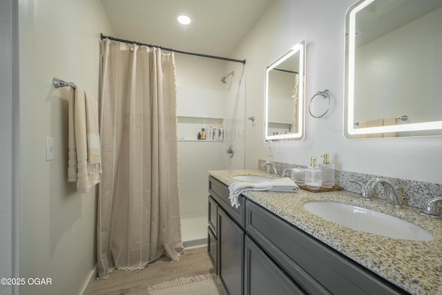 full bath featuring double vanity, wood finished floors, a shower with curtain, and a sink