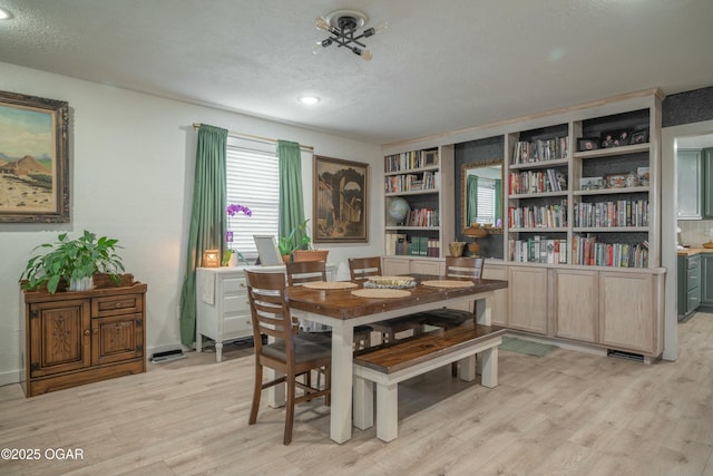 dining area featuring a textured ceiling and light wood finished floors