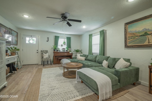 living area featuring a wealth of natural light, a ceiling fan, and light wood finished floors