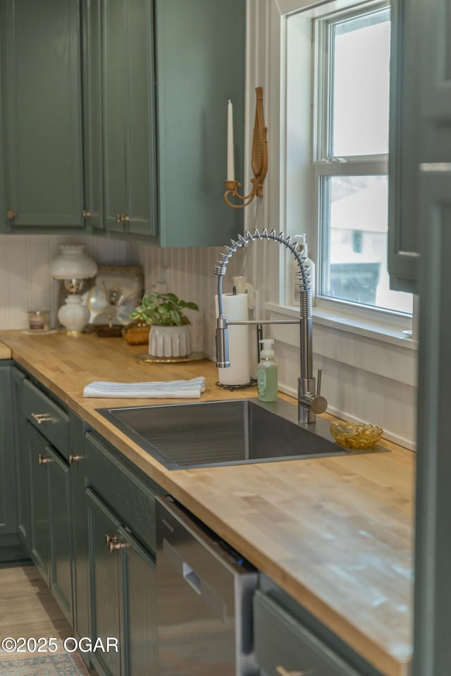 kitchen featuring a sink, stainless steel dishwasher, green cabinets, and butcher block counters