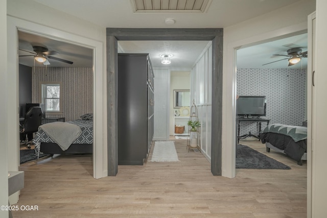 hall with baseboards, wallpapered walls, an accent wall, and light wood-style floors