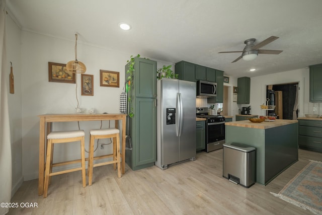 kitchen with butcher block countertops, a ceiling fan, light wood-style floors, appliances with stainless steel finishes, and green cabinets