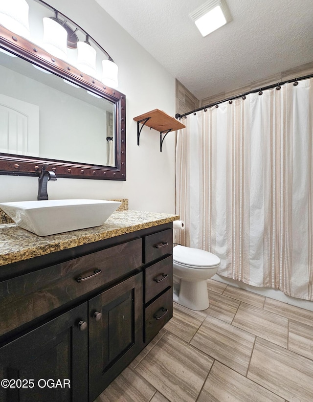 bathroom featuring vanity, toilet, and a textured ceiling