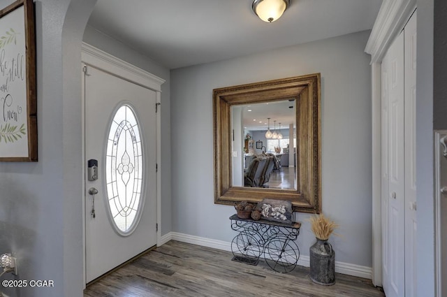 entrance foyer featuring baseboards, arched walkways, and wood finished floors