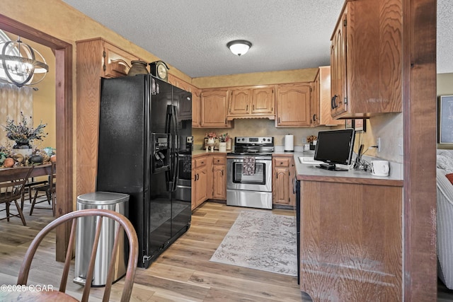 kitchen with stainless steel electric stove, light countertops, light wood-type flooring, black fridge, and a textured ceiling