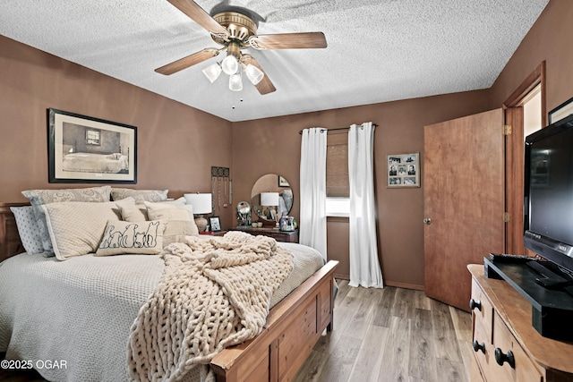 bedroom featuring ceiling fan, light wood-type flooring, and a textured ceiling