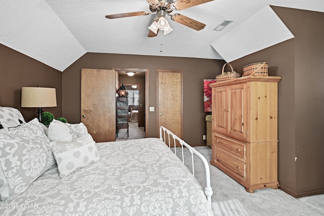 bedroom featuring a ceiling fan, visible vents, vaulted ceiling, a textured ceiling, and light colored carpet