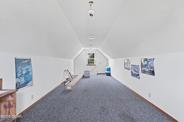 interior space featuring baseboards, a textured ceiling, carpet flooring, and vaulted ceiling