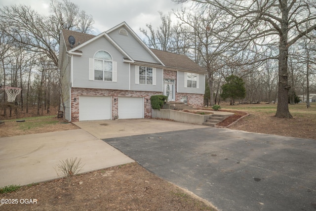 split foyer home with brick siding, driveway, a shingled roof, and a garage