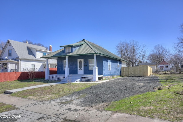 bungalow featuring a porch, fence, and metal roof