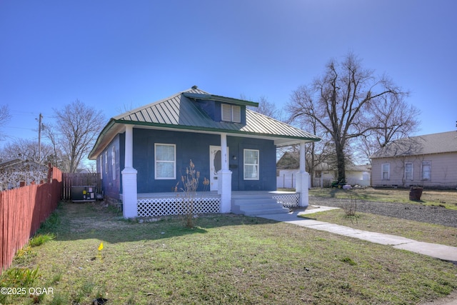 bungalow featuring covered porch, metal roof, a front lawn, and fence