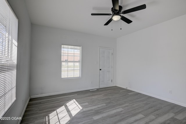 empty room featuring ceiling fan, baseboards, and wood finished floors