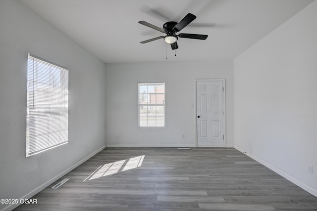 unfurnished room with baseboards, wood finished floors, visible vents, and ceiling fan