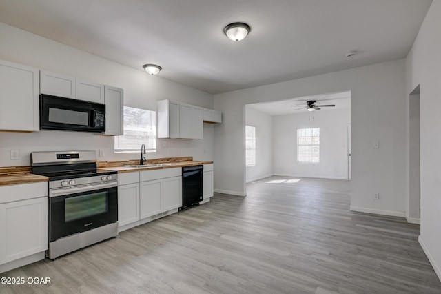 kitchen with black microwave, butcher block counters, stainless steel range with electric cooktop, light wood-style floors, and a sink