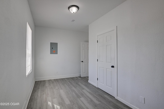 unfurnished bedroom featuring electric panel, baseboards, and wood finished floors