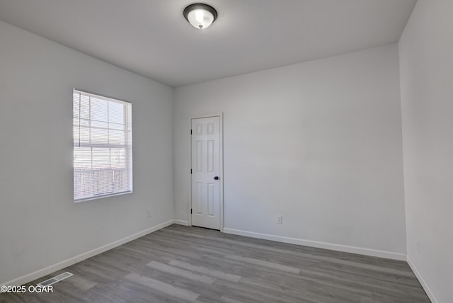 empty room featuring visible vents, baseboards, and wood finished floors