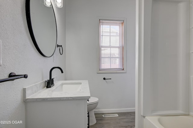 bathroom with visible vents, toilet, wood finished floors, baseboards, and vanity