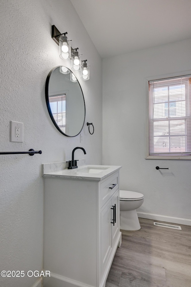 bathroom with visible vents, plenty of natural light, vanity, and toilet