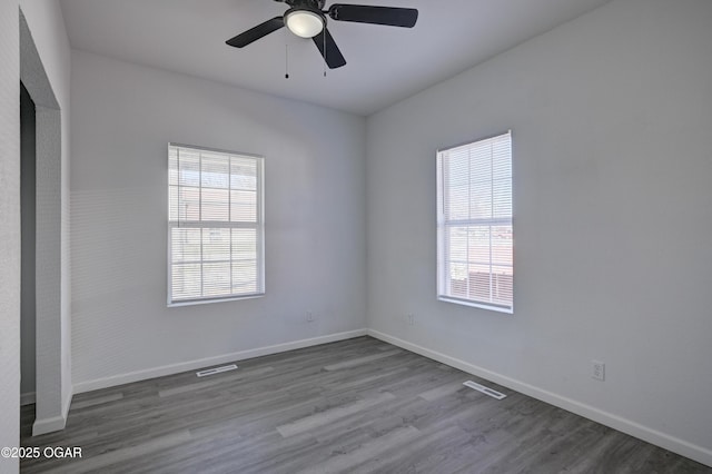 unfurnished room featuring a ceiling fan, visible vents, wood finished floors, and baseboards