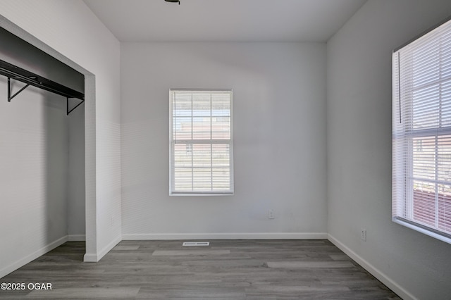 unfurnished bedroom with visible vents, wood finished floors, and baseboards