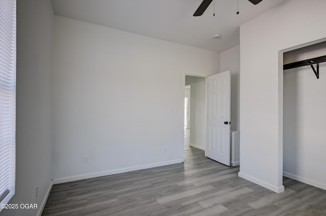 unfurnished bedroom featuring wood finished floors, baseboards, a closet, and ceiling fan