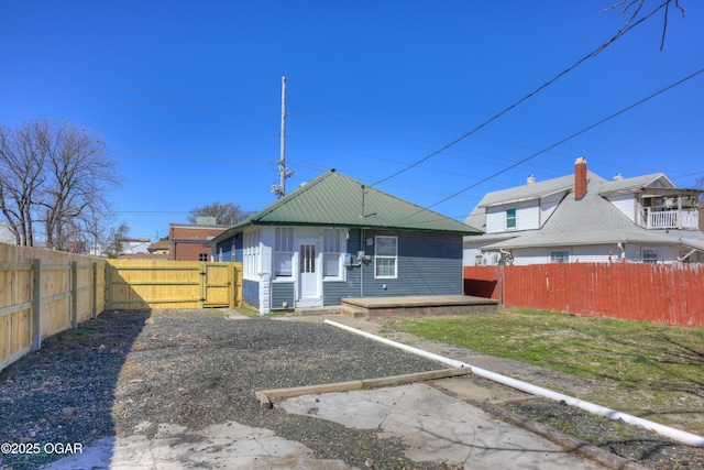 rear view of property featuring a gate and fence