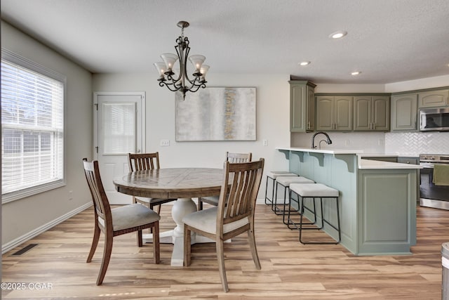 dining space featuring baseboards, visible vents, light wood finished floors, recessed lighting, and a chandelier