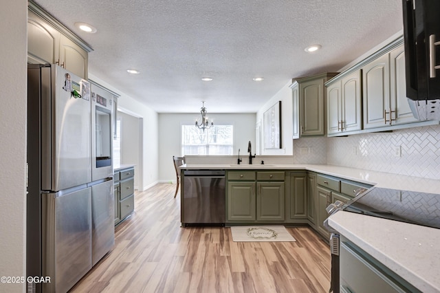 kitchen with light wood-style flooring, a sink, backsplash, stainless steel appliances, and light countertops