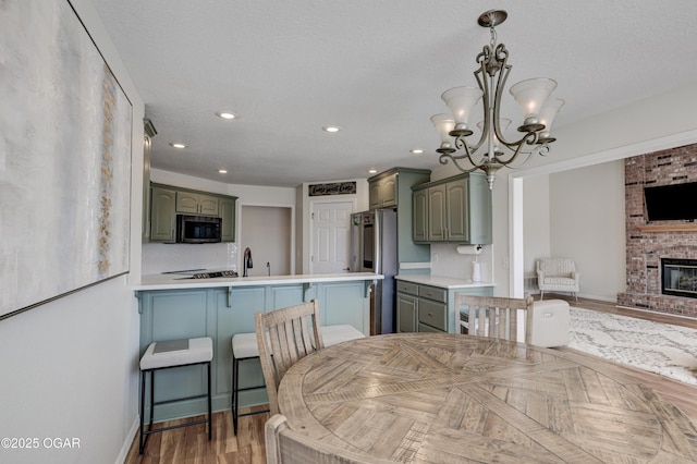 dining room featuring wood finished floors, baseboards, an inviting chandelier, recessed lighting, and a fireplace