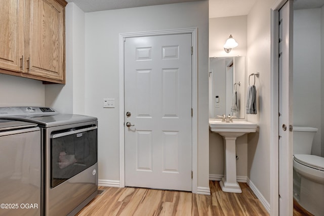 laundry room featuring washer and dryer, baseboards, light wood-style floors, and laundry area