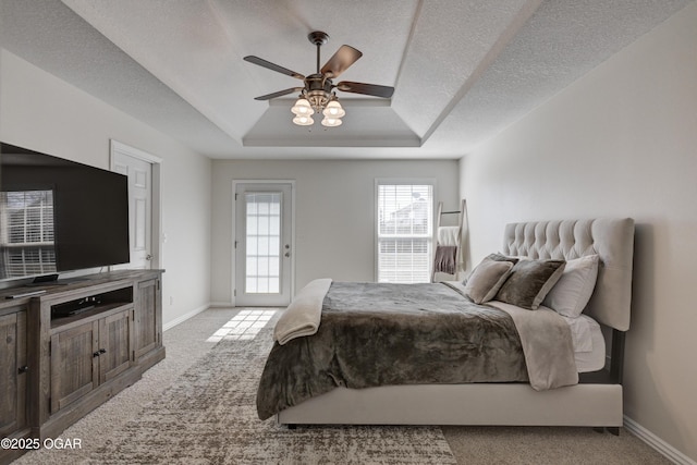 bedroom featuring a tray ceiling, carpet flooring, baseboards, and a textured ceiling