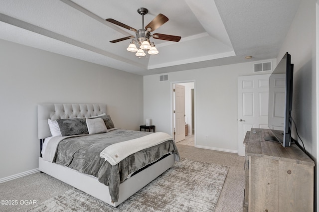 bedroom featuring baseboards, a tray ceiling, light carpet, and visible vents