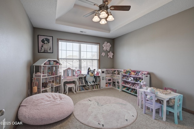 rec room with a raised ceiling, a ceiling fan, visible vents, and carpet floors