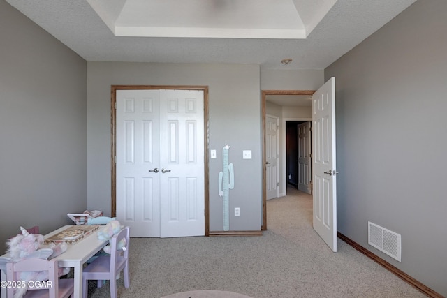 bedroom featuring visible vents, light carpet, a textured ceiling, and baseboards