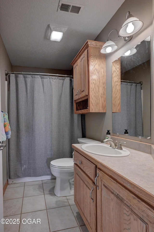 bathroom with visible vents, toilet, vanity, tile patterned floors, and a textured ceiling