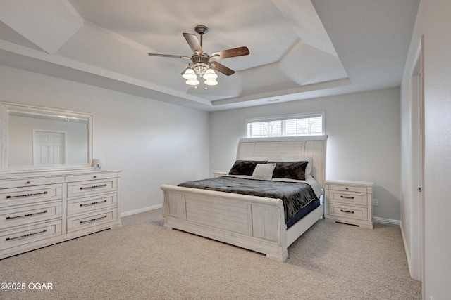 bedroom with a tray ceiling, a ceiling fan, baseboards, and light carpet