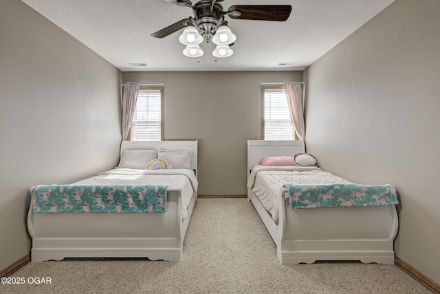 bedroom with baseboards, a textured ceiling, carpet floors, and a ceiling fan