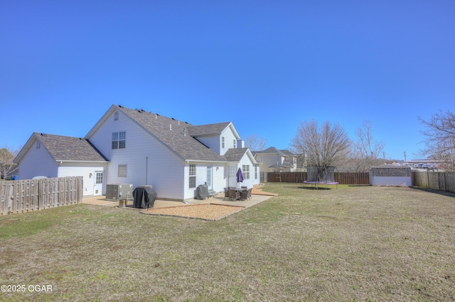 rear view of house featuring a patio area, a fenced backyard, a yard, and a trampoline