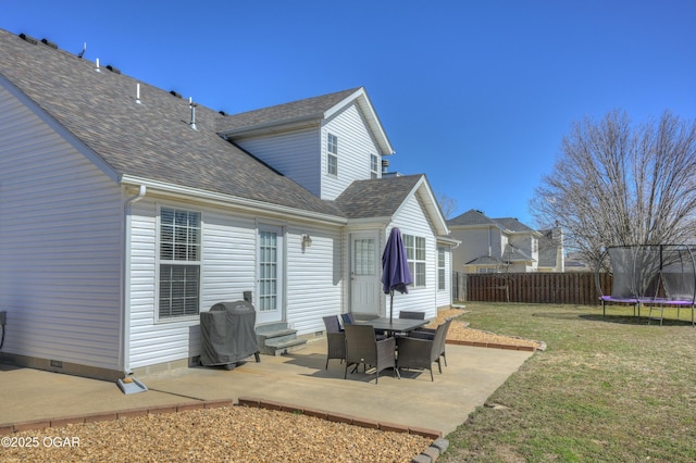 back of property with entry steps, a trampoline, fence, a yard, and crawl space