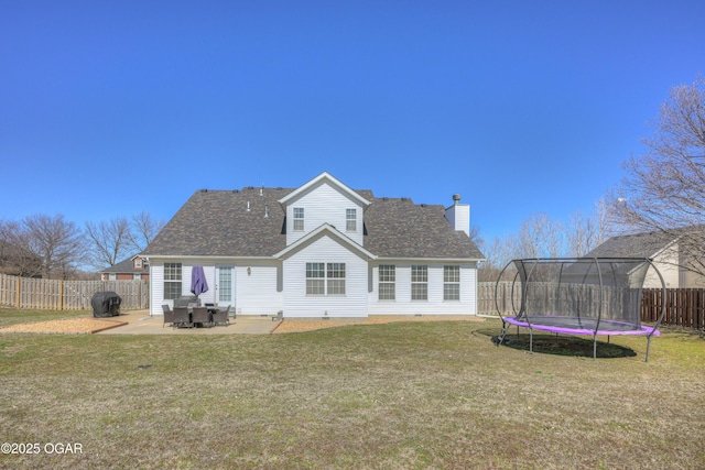 rear view of property featuring a trampoline, a lawn, a chimney, a fenced backyard, and a patio area