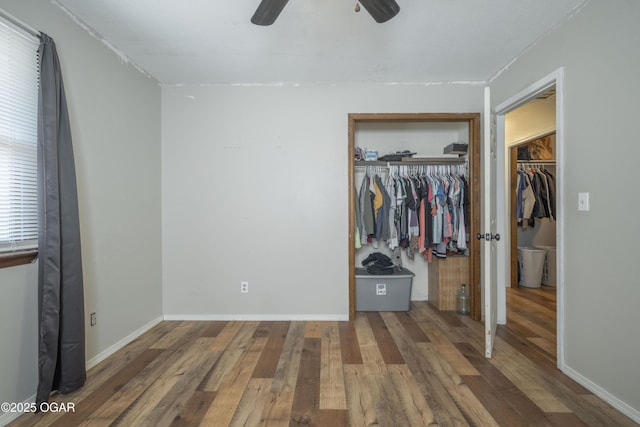 unfurnished bedroom featuring a ceiling fan, wood finished floors, a closet, and baseboards