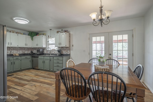 dining space featuring french doors, light wood-type flooring, and an inviting chandelier