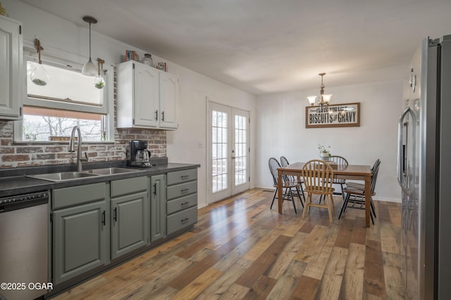 kitchen with a sink, dark countertops, freestanding refrigerator, french doors, and dishwashing machine