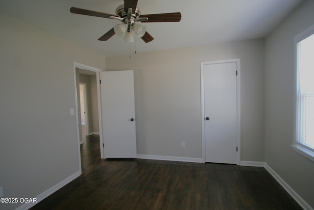 unfurnished bedroom with dark wood-type flooring, a ceiling fan, and baseboards