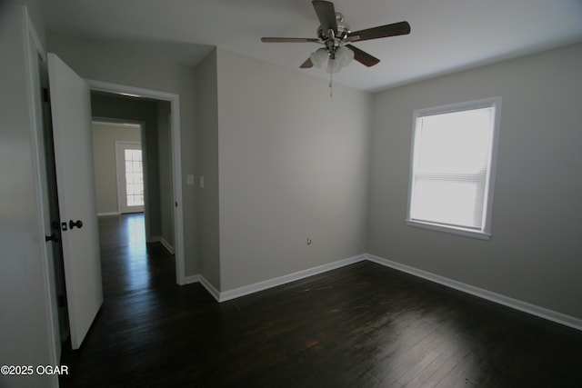 spare room with baseboards, dark wood-type flooring, and a ceiling fan