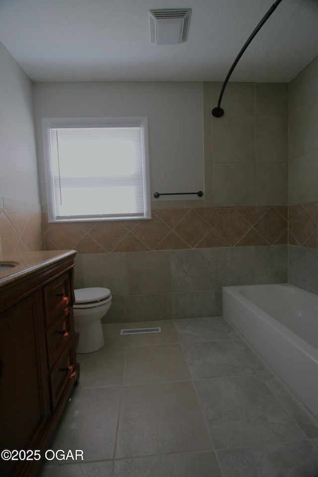 bathroom featuring tile patterned flooring, visible vents, toilet, and tile walls