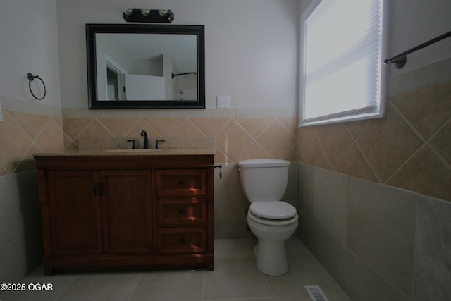 bathroom featuring tile patterned flooring, tile walls, toilet, and vanity