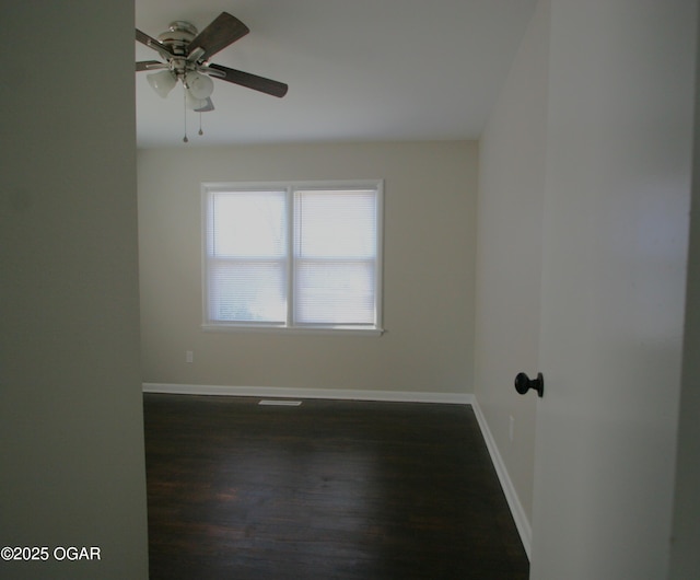 unfurnished room featuring baseboards, ceiling fan, and dark wood finished floors