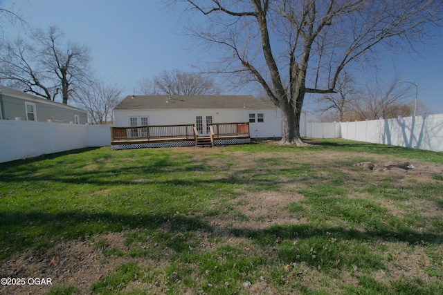 rear view of house featuring french doors, a fenced backyard, a yard, and a wooden deck